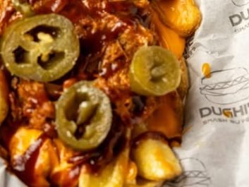 Patatas cargadas con carne, queso y jalapeños sobre papel impreso con el logotipo de Dughi's.