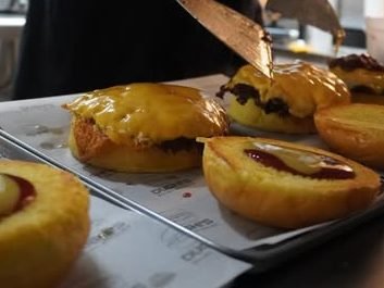 El cocinero coloca las carnes sobre los panes con una espátula durante el pase.